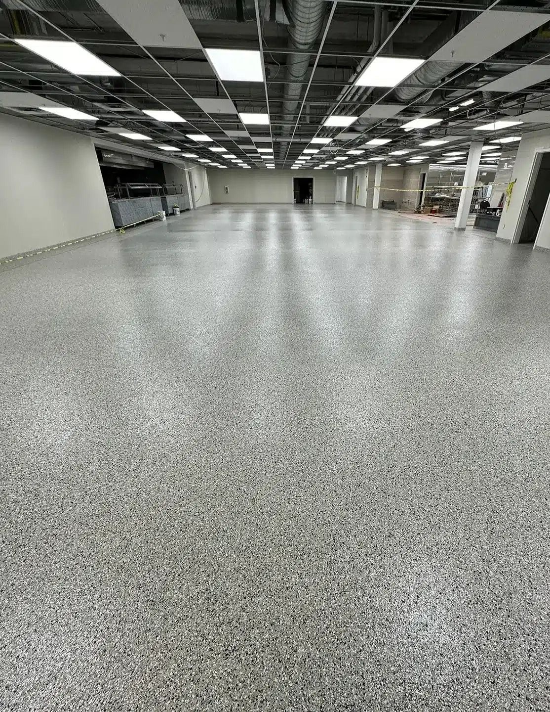 Lantai epoxy flake abu-abu pada ruang komersial luas